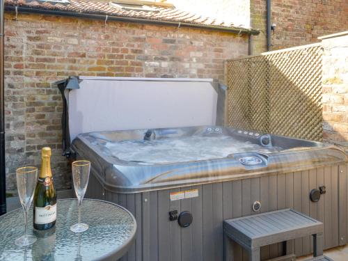 a hot tub with a bottle of wine and two glasses at The Dairy Uk13198 in Butterwick