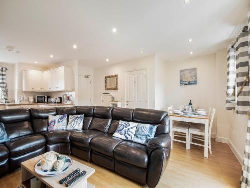 a living room with a leather couch and a kitchen at Harbour Retreat in Garlieston