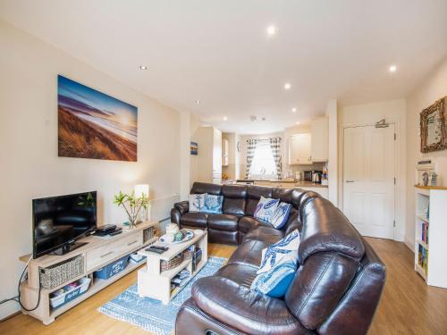 a living room with a leather couch and a television at Harbour Retreat in Garlieston