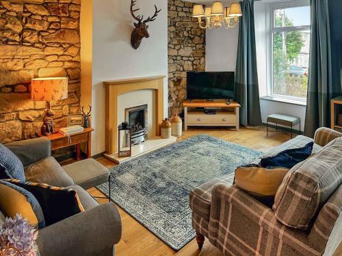a living room with a couch and a fireplace at Bertram Cottage in Swarland