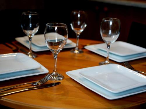 a wooden table with plates and wine glasses on it at Bertram Cottage in Swarland
