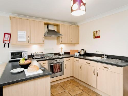 a kitchen with wooden cabinets and black counter tops at Close Cottage - W41944 in Filey