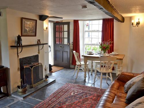 a living room with a couch and a table and a fireplace at Brock Cottage in Broughton in Furness