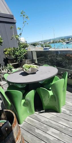 a table and chairs on a deck with a view of the ocean at Napier Apartment Ahuriri in Napier