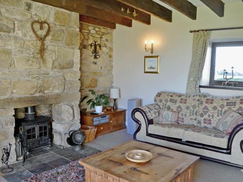 a living room with a couch and a stone fireplace at Sandsedge Cottage in Ellington
