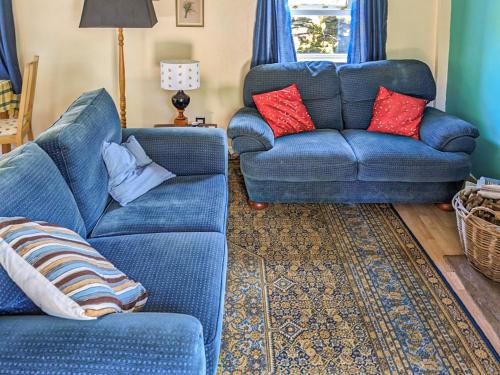 a blue couch and two chairs in a living room at Port Righ Cottage in Carradale