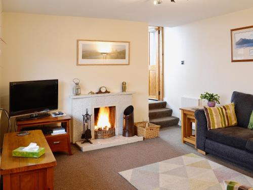a living room with a fireplace and a television at Bayview in Collieston
