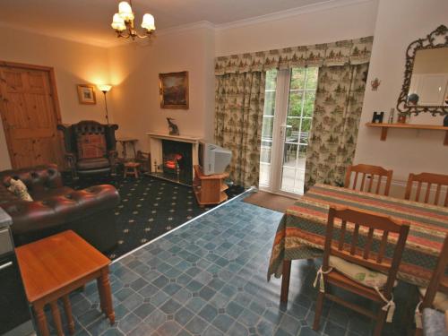 a living room with a couch a table and a fireplace at Lochview Barn in Strathyre