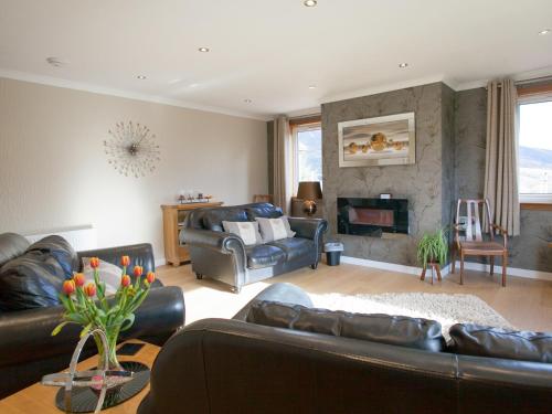 a living room with leather furniture and a fireplace at Strone Farm House in Torcastle