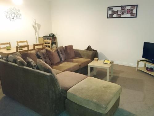a living room with a brown couch and a table at Belle Isle Cottage in Haworth
