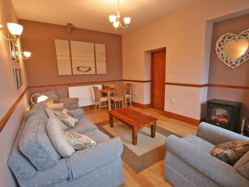 a living room with two couches and a fireplace at Granary Cottage Whittingham in Whittingham