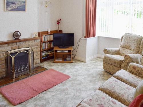 a living room with a fireplace and a television at Rose Garth in Robin Hood's Bay