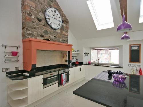 a kitchen with a large clock on a stone wall at Dornock Brow Cottage in Dornock