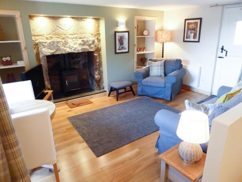 a living room with a blue couch and a fireplace at Crosskeys Cottage in Shandon