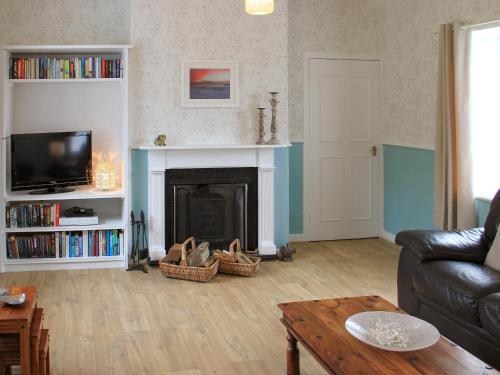 a living room with a couch and a fireplace at Palmallet Cottage in Whithorn