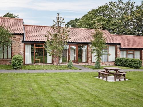 a building with a picnic table in the grass at Cobble Cottage - W41945 in Filey