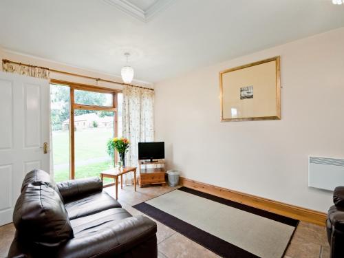a living room with a leather couch and a television at Cobble Cottage - W41945 in Filey
