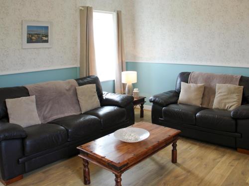 a living room with two leather couches and a coffee table at Palmallet Cottage in Whithorn