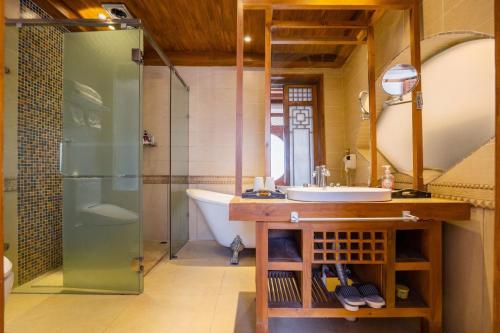 a bathroom with a tub and a sink and a shower at Shile Inn in Lijiang
