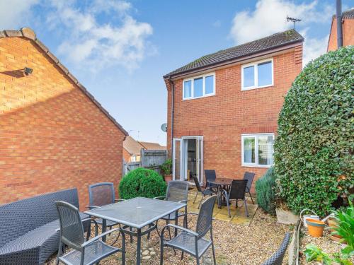 a patio with tables and chairs in front of a brick house at Chaucer Rise in Exmouth