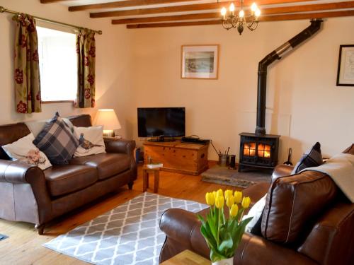 a living room with leather furniture and a fireplace at Knoppingsholme Stable in Greenhaugh