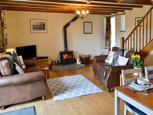 a living room with leather furniture and a fireplace at Knoppingsholme Stable in Greenhaugh