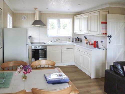 a kitchen with white cabinets and a table and chairs at Ash Lodge in Nawton