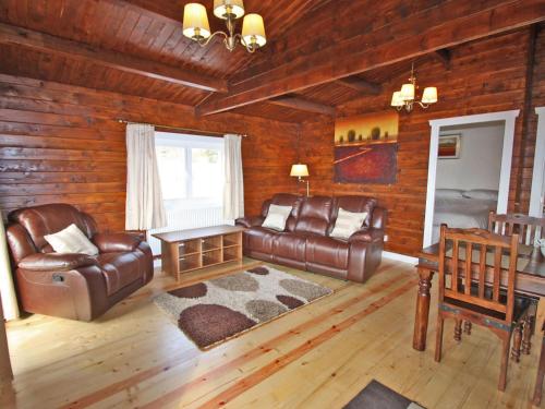 a living room with a leather couch and a table at White Springs - Lake View in Llanedy