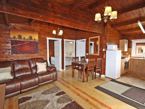 a living room with a leather couch and a table at White Springs - Lake View in Llanedy