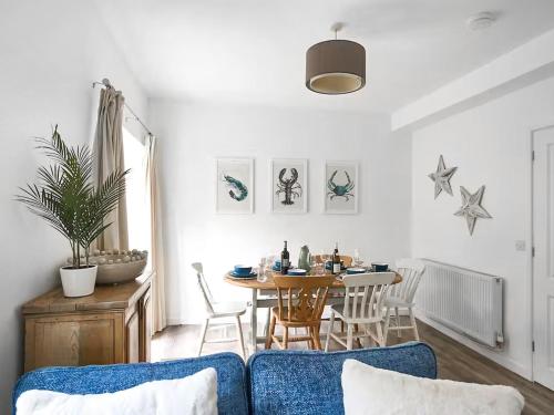 a living room with a table and a blue couch at Surf Cottage in Cromer