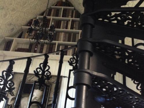 a stair case with a wrought iron railing with books at Silverleaf Cottage in Rye