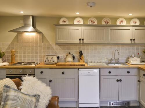 a kitchen with white cabinets and a sink at The Old Cobblers Cottage in Bakewell