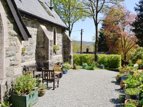 a stone building with benches and potted plants at St John The Baptist in Capel Curig