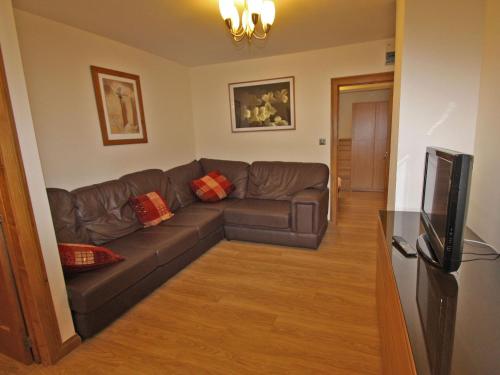 a living room with a couch and a television at Springfield Court - Lakeview in Bonvilston