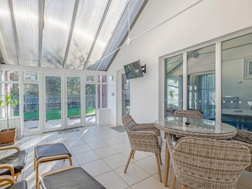 a living room with a table and chairs and windows at The Beeches in Sea Palling
