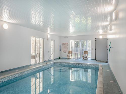 a swimming pool with two chairs in a building at The Beeches in Sea Palling
