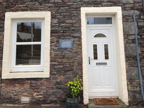 a white door and two windows on a brick building at Heather Cottage in Lauder