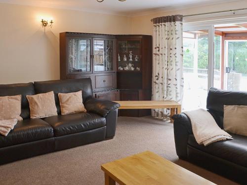 a living room with a leather couch and a table at The Willows Red Row in East Chevington