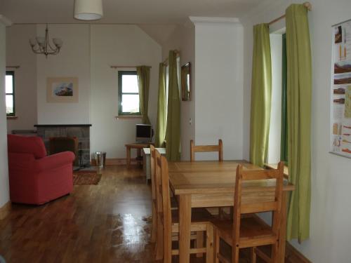 a dining room with a wooden table and a red couch at Taigh Uaine in Culkein