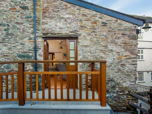 a balcony with a wooden railing next to a stone building at Mill Balcony in Ashsprington