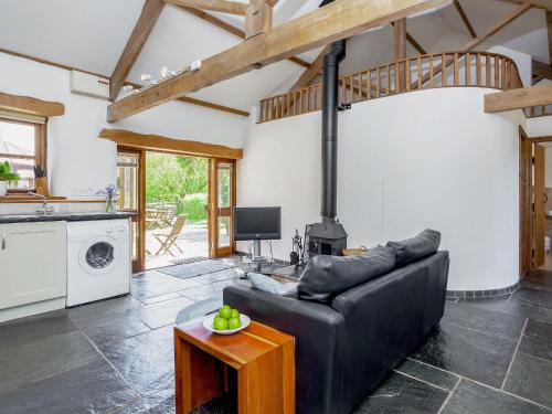 a living room with a black leather couch and a stove at Old Dairy in Chulmleigh