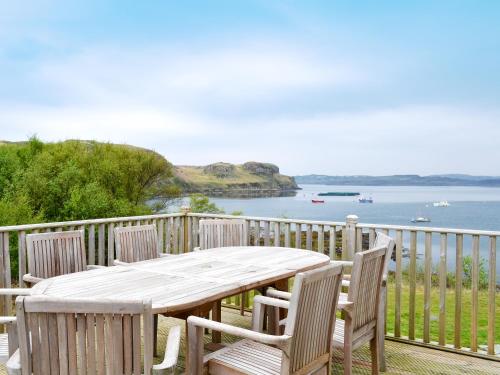 a wooden table and chairs on a deck with a view of the water at Shelduck House in Port na Long
