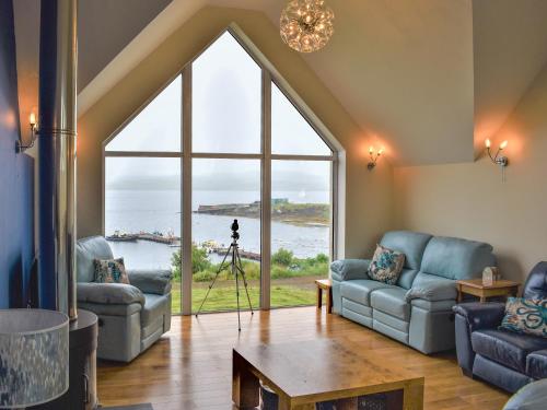 a living room with couches and a large window at Shelduck House in Port na Long