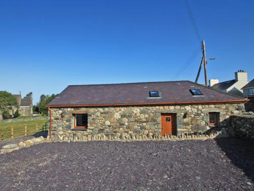 a stone building with a brown roof at Yr Hen Weithdy in Llanllechid