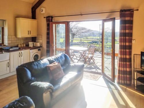 a living room with a couch in front of a sliding glass door at Yr Hen Weithdy in Llanllechid