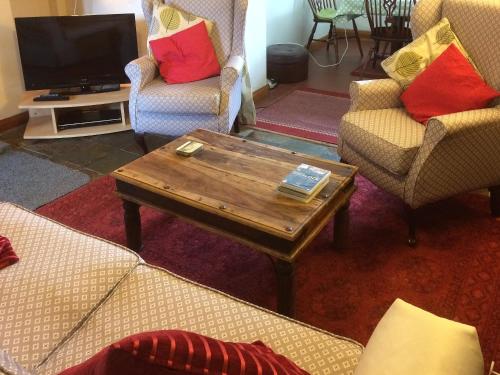 a living room with two chairs and a coffee table at Bellypig Cottage in Bellerby
