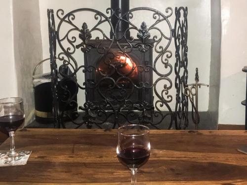 two glasses of wine on a wooden table with a fireplace at Bellypig Cottage in Bellerby