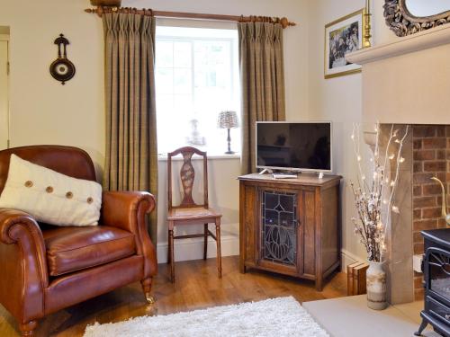 a living room with a leather chair and a television at Mill Race Cottage in Bakewell