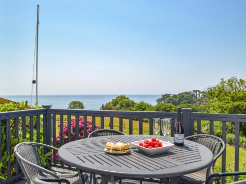 a table with a bowl of tomatoes and a bottle of wine at Seaview Cottage - Uk44707 in Amroth