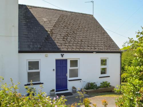 a white cottage with a blue door at Seaview Cottage - Uk44707 in Amroth